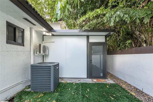 view of outdoor structure featuring a wall mounted air conditioner and central AC unit