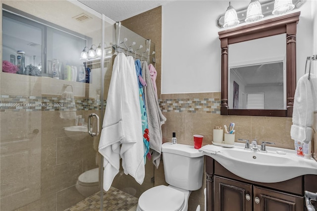 bathroom with vanity, toilet, a textured ceiling, tile walls, and a shower with shower door