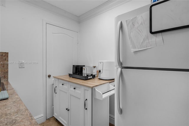 kitchen with crown molding, white cabinets, wooden counters, and white refrigerator