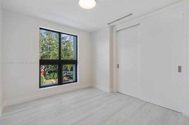 unfurnished bedroom with light hardwood / wood-style floors and multiple windows