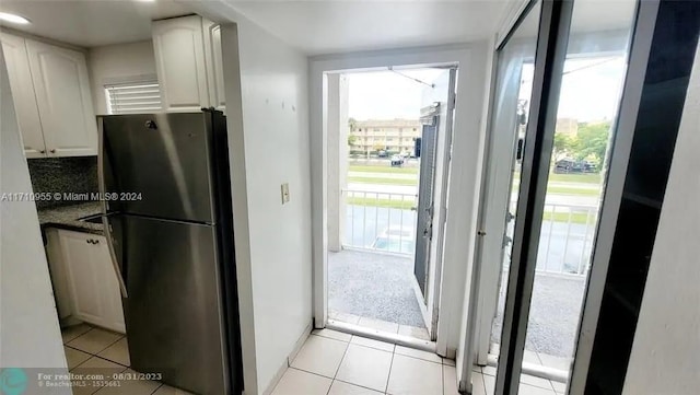 kitchen with plenty of natural light, stainless steel fridge, decorative backsplash, and light tile patterned floors