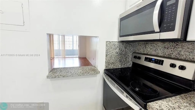 kitchen featuring backsplash, light stone countertops, white cabinetry, and stainless steel appliances