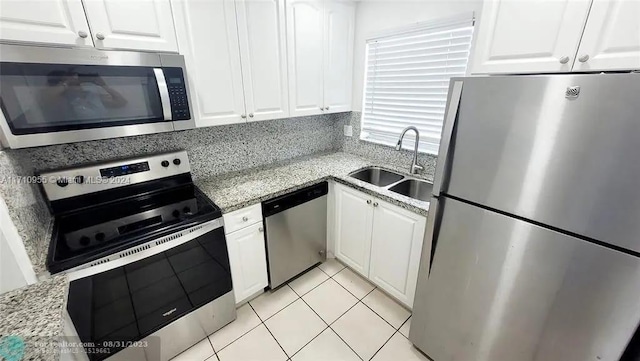 kitchen featuring white cabinets, light stone counters, sink, and stainless steel appliances