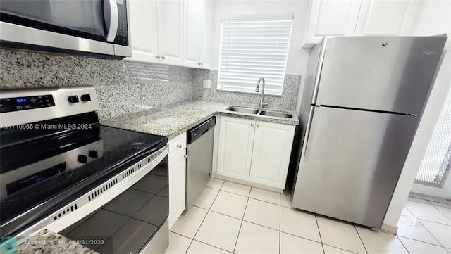 kitchen with sink, light stone countertops, light tile patterned flooring, white cabinetry, and stainless steel appliances