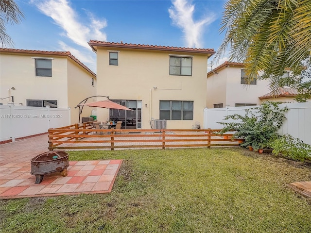 rear view of house with a lawn, an outdoor fire pit, and a patio