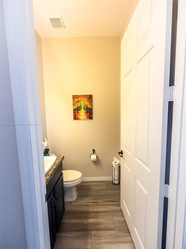 bathroom with vanity, toilet, and wood-type flooring