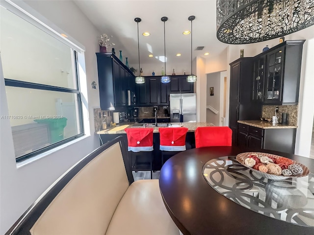 kitchen with stainless steel refrigerator with ice dispenser, tasteful backsplash, pendant lighting, and sink