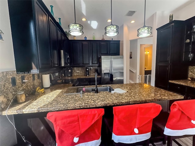 kitchen featuring sink, stainless steel appliances, kitchen peninsula, decorative light fixtures, and decorative backsplash