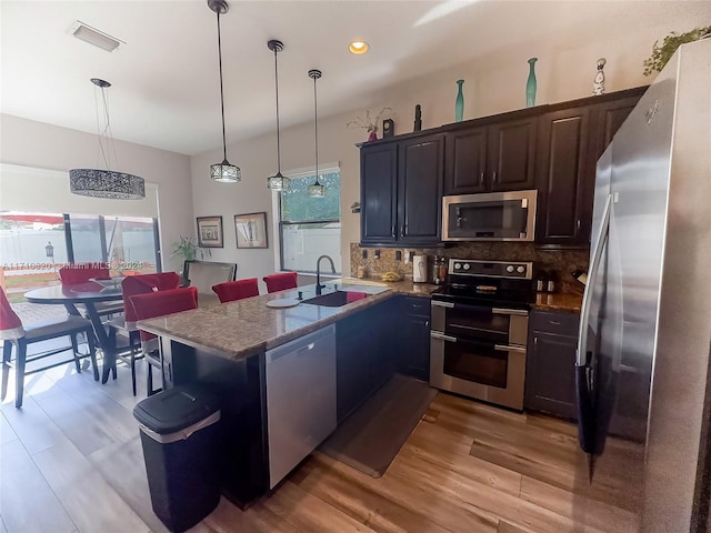 kitchen featuring plenty of natural light, pendant lighting, light wood-type flooring, and appliances with stainless steel finishes