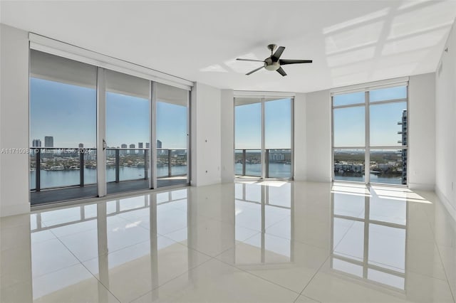 spare room with a water view, a healthy amount of sunlight, floor to ceiling windows, and light tile patterned flooring