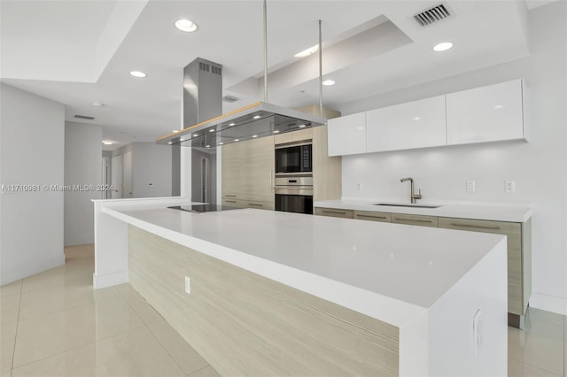 kitchen with sink, white cabinets, a large island, light tile patterned floors, and black appliances