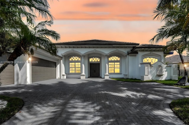 mediterranean / spanish house with a garage, decorative driveway, and stucco siding