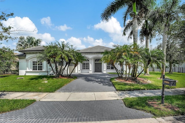 mediterranean / spanish home with decorative driveway, a front yard, fence, and stucco siding