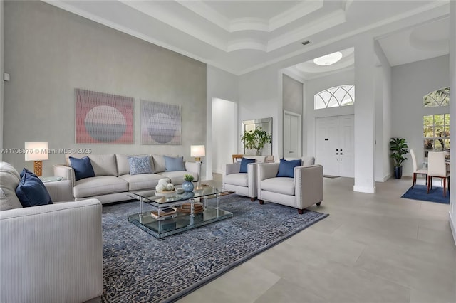 living area featuring visible vents, ornamental molding, a raised ceiling, and a towering ceiling