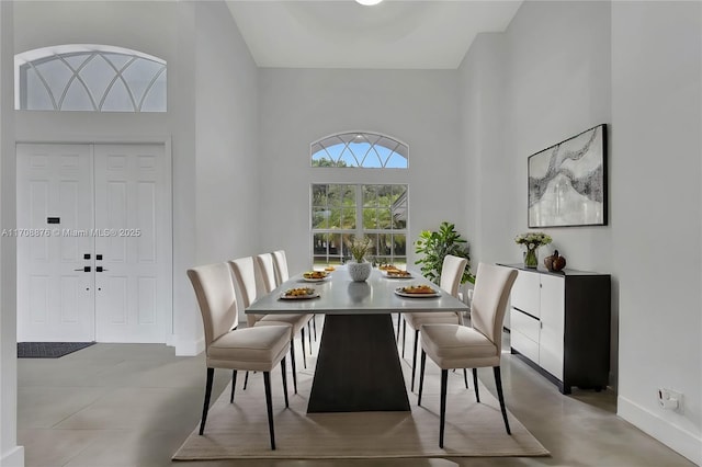 dining space with baseboards and a high ceiling