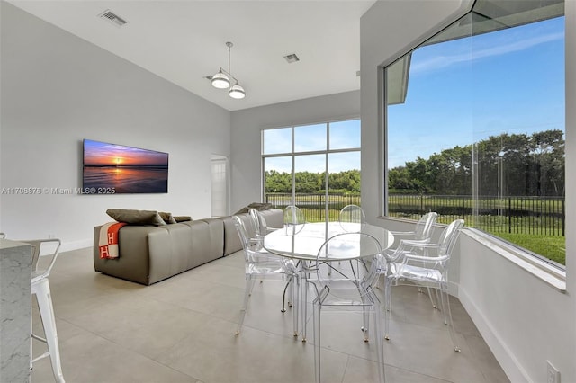 unfurnished dining area featuring vaulted ceiling, light tile patterned flooring, visible vents, and baseboards