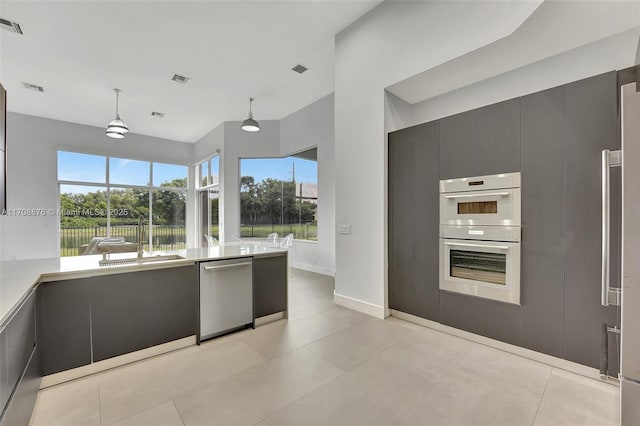 kitchen with pendant lighting, light tile patterned floors, white double oven, and dishwasher