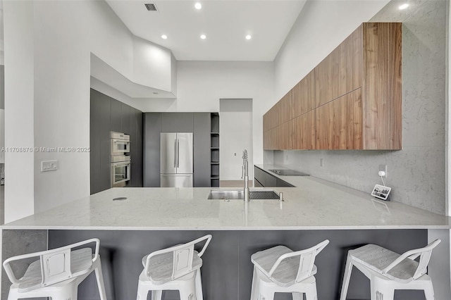 kitchen with sink, a breakfast bar area, stainless steel refrigerator, and kitchen peninsula