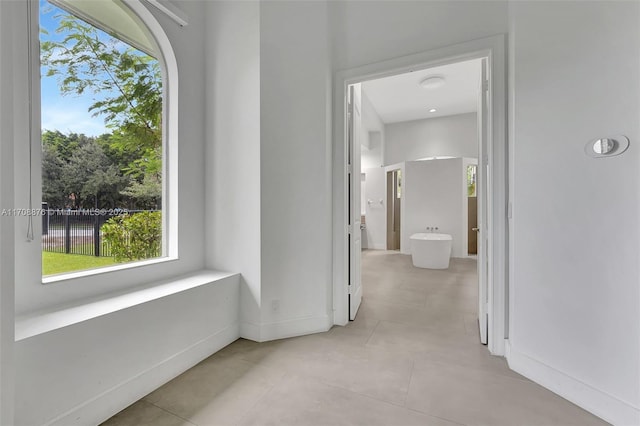 corridor with light tile patterned floors and baseboards