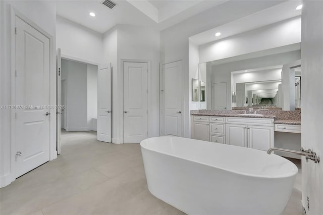 bathroom featuring vanity, tile patterned flooring, and a washtub