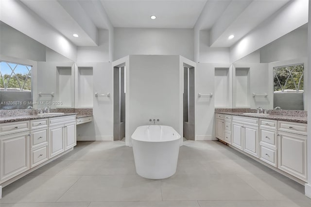 bathroom featuring vanity, a towering ceiling, a wealth of natural light, and a tub