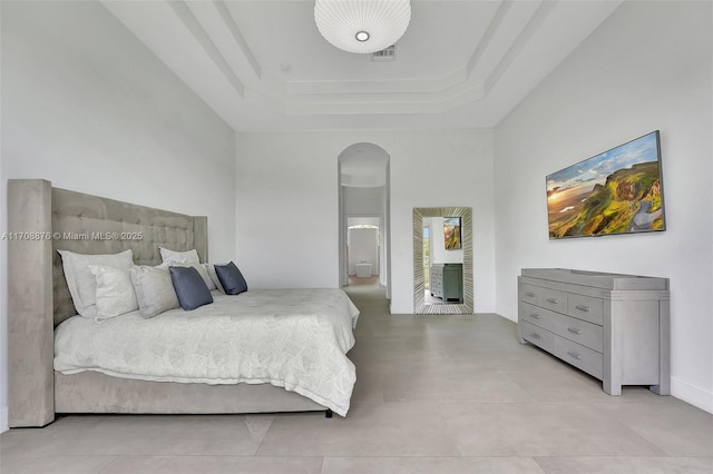 bedroom featuring a raised ceiling and a high ceiling