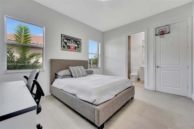 bedroom with light tile patterned flooring and ensuite bath