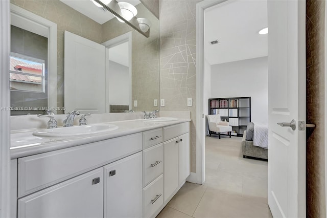 full bathroom with tile patterned flooring, a sink, tile walls, and double vanity