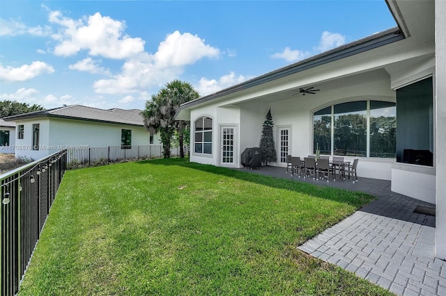 rear view of property featuring a lawn, a patio, and ceiling fan