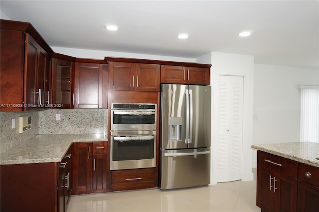 kitchen featuring light stone counters, stainless steel appliances, and tasteful backsplash