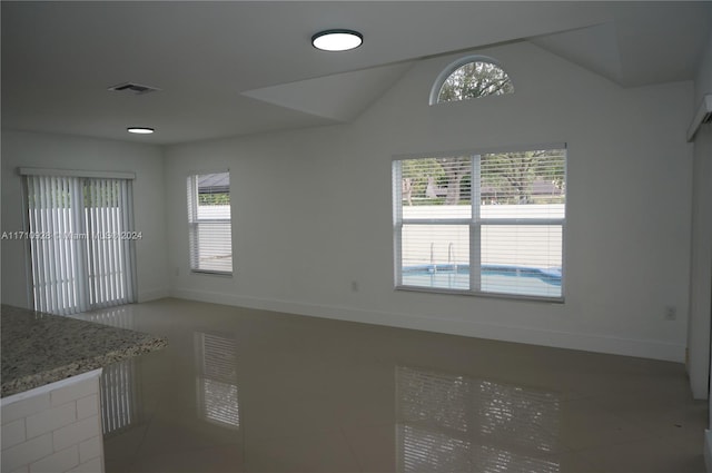 interior space with tile patterned floors, a wealth of natural light, and lofted ceiling