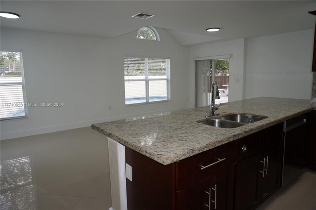 kitchen featuring stainless steel dishwasher, light stone counters, light tile patterned floors, and sink