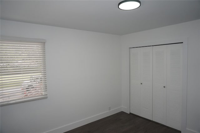 unfurnished bedroom with dark hardwood / wood-style flooring and a closet