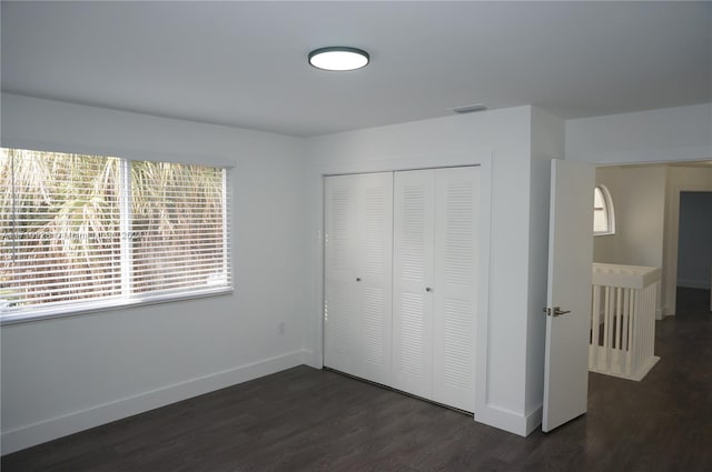 unfurnished bedroom featuring a closet and dark hardwood / wood-style floors