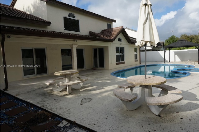 back of property featuring a gazebo, a patio, and a fenced in pool