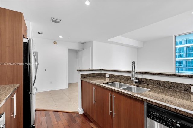 kitchen featuring dark stone countertops, light wood-type flooring, sink, and appliances with stainless steel finishes