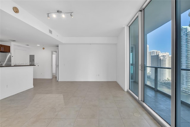 unfurnished room with floor to ceiling windows, electric panel, and light tile patterned floors