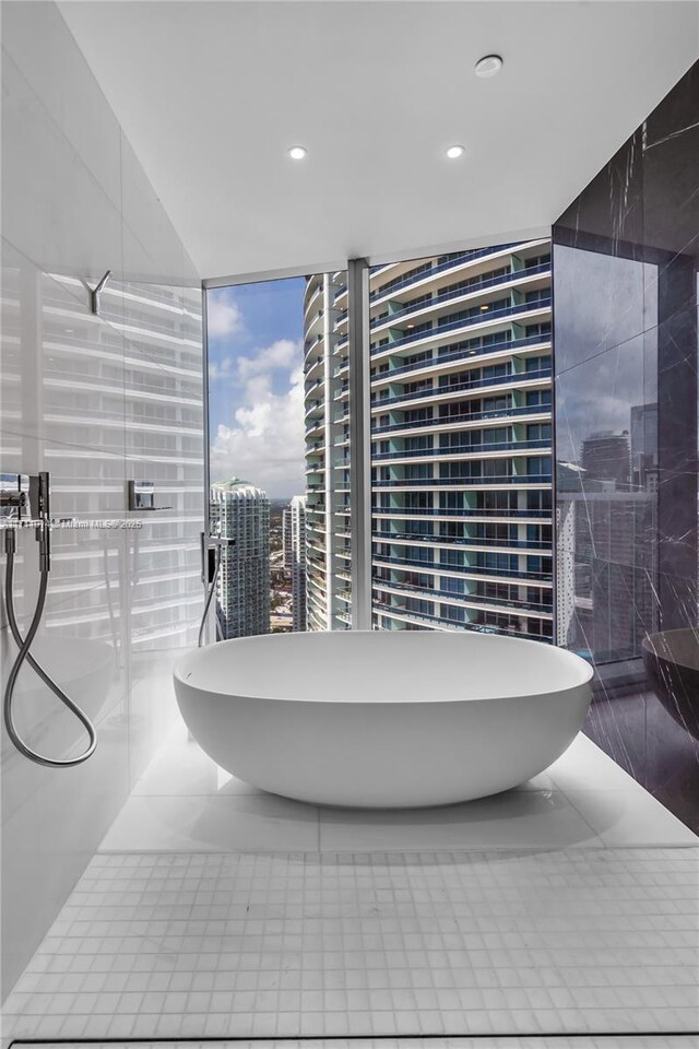 bathroom with tile patterned flooring, a wall of windows, and a bathtub