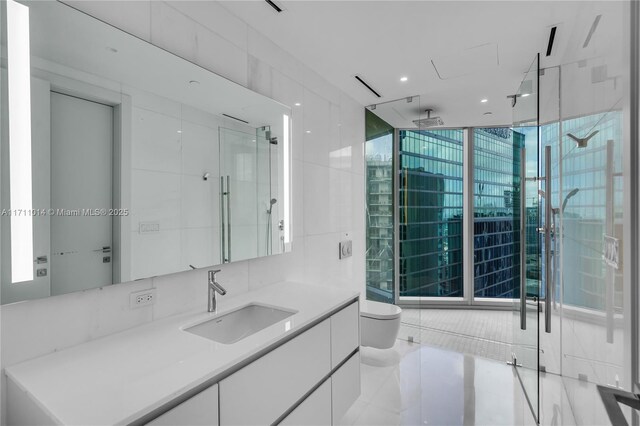 bathroom featuring toilet, walk in shower, tile walls, a wall of windows, and vanity