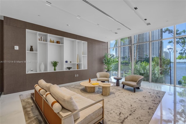 living room featuring a water view, a healthy amount of sunlight, and floor to ceiling windows