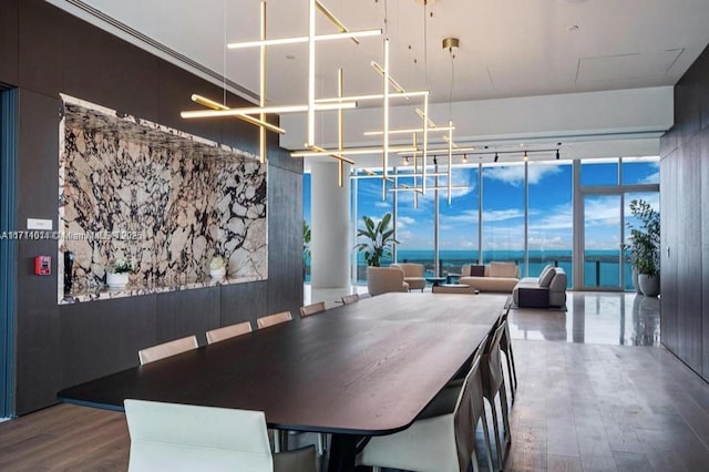 dining space featuring floor to ceiling windows, hardwood / wood-style flooring, a chandelier, and a water view