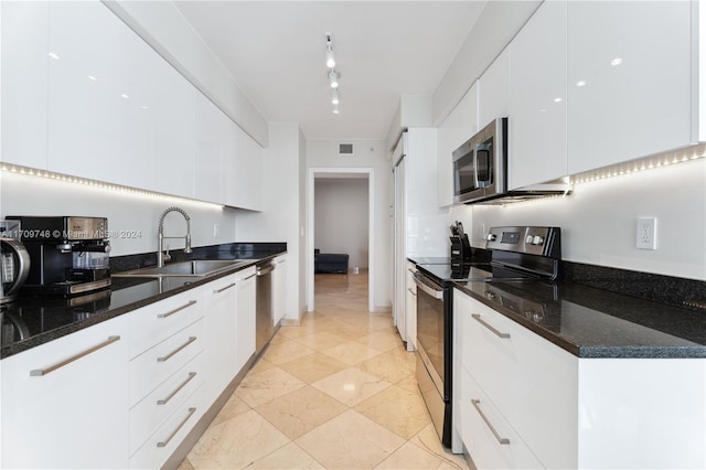 kitchen with dark stone counters, sink, white cabinets, and stainless steel appliances