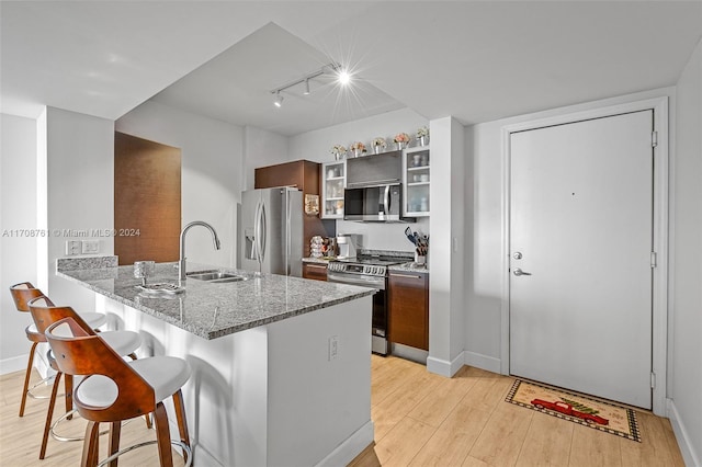 kitchen featuring kitchen peninsula, a kitchen breakfast bar, light wood-type flooring, stainless steel appliances, and sink