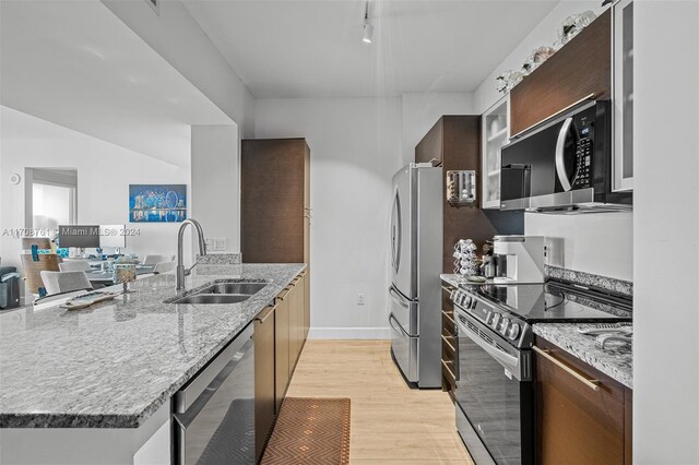 kitchen with sink, light hardwood / wood-style flooring, light stone counters, dark brown cabinetry, and stainless steel appliances