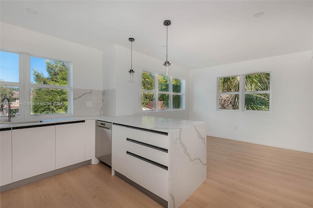 kitchen with white cabinets, kitchen peninsula, hanging light fixtures, and sink