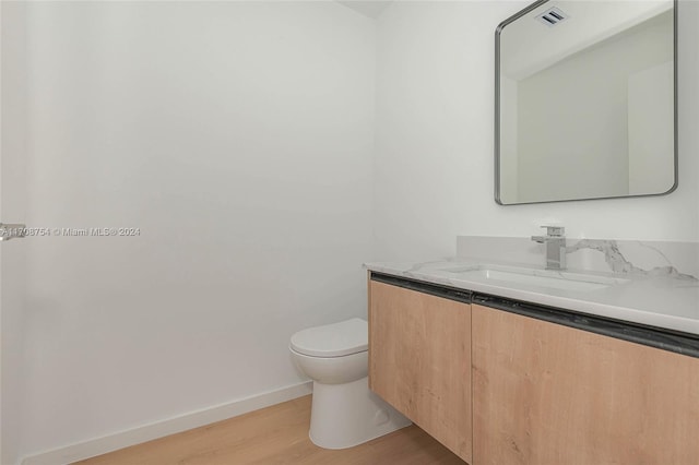 bathroom with hardwood / wood-style floors, vanity, and toilet