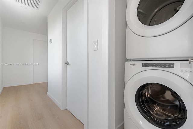 clothes washing area featuring light hardwood / wood-style flooring and stacked washer / drying machine