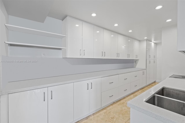 kitchen with light tile patterned flooring, white cabinetry, and sink