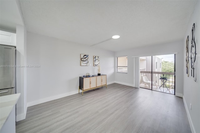 unfurnished living room featuring light hardwood / wood-style floors and a textured ceiling