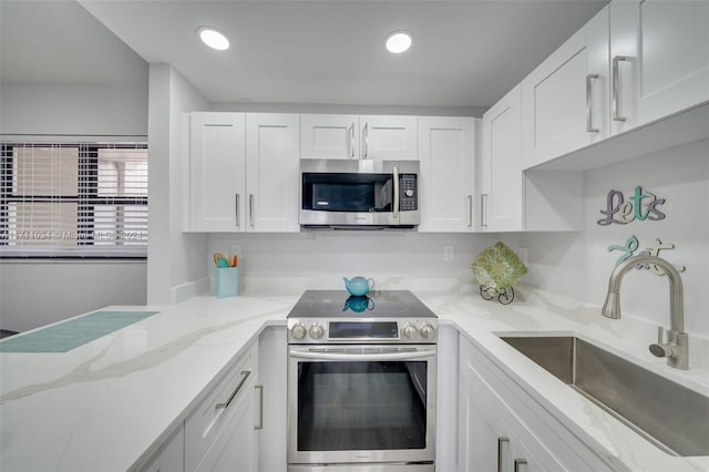 kitchen featuring light stone countertops, white cabinetry, sink, and stainless steel appliances